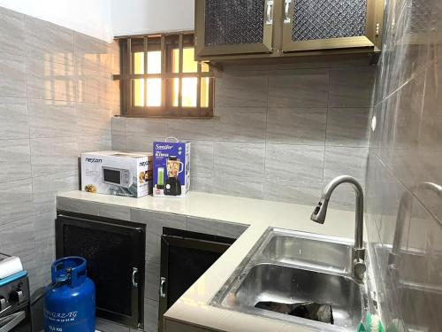 a kitchen with a sink and a microwave at RESIDENCE Chez PETER in Alakopé