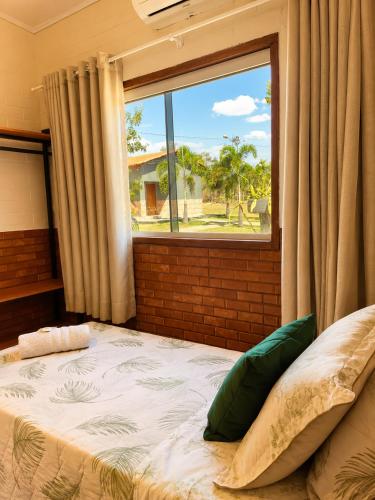 a bed in a room with a large window at Chalés Araras do Vale in Colinas Do Sul