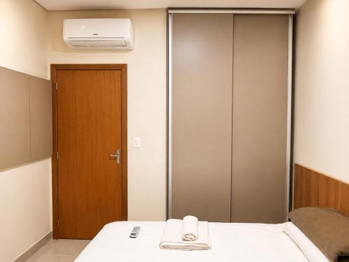 a room with a bed with a mirror and a door at Vêneto Flat Residence (AP-13) in Primavera do Leste