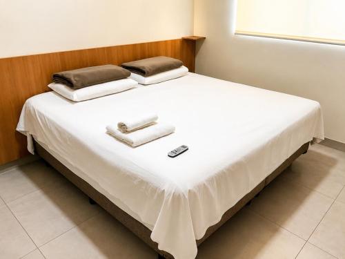 a white bed with two pillows on top of it at Vêneto Flat Residence (AP-13) in Primavera do Leste