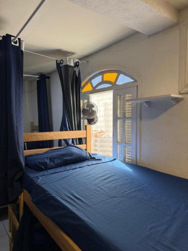 a bedroom with a bed and a window at Primos Hostel & House in Búzios