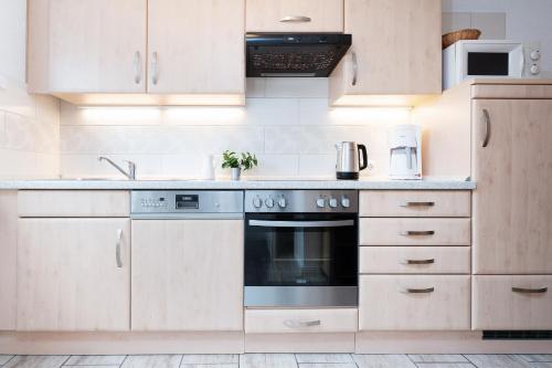 a kitchen with white cabinets and a stove top oven at Huus 41 in Wulfen auf Fehmarn