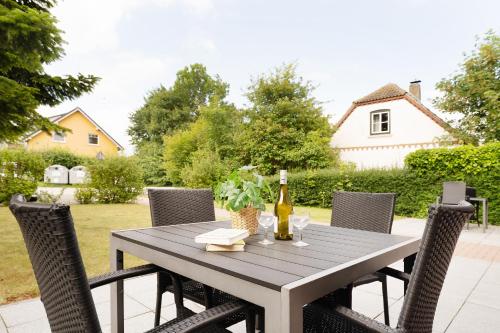 a wooden table with chairs and a bottle of wine at Huus 41 in Wulfen auf Fehmarn