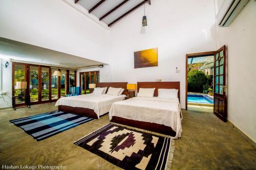a bedroom with two beds and a pool at Serendipity Lake Villa in Panadura