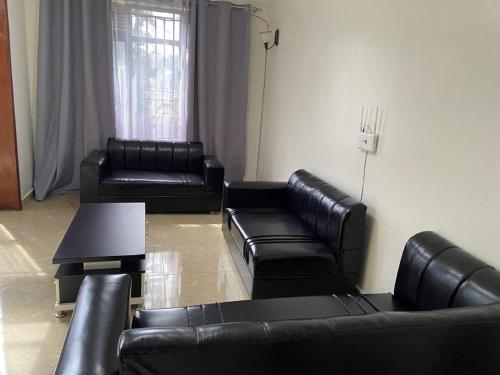 a living room with black leather couches and a table at Khartoum Nights in Kigali