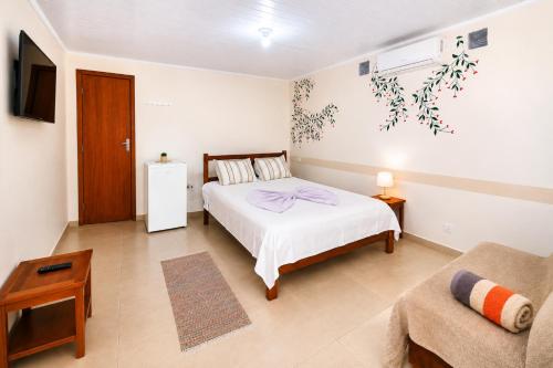 a bedroom with a bed and a couch at Mandinga Guest house in São Tomé