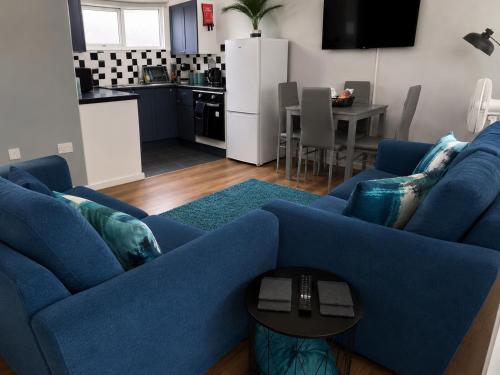 a living room with a blue couch and a kitchen at Seashells - Chalet 25 in Greatstone