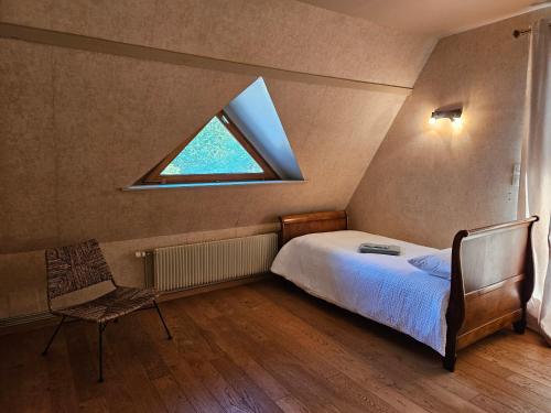 a bedroom with a window and a bed and a chair at Le Clos des Argillières in Le Perrey