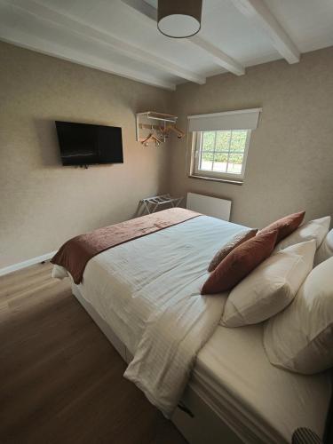 a bedroom with a large bed with a tv on the wall at La Brise des Fagnes in Jalhay