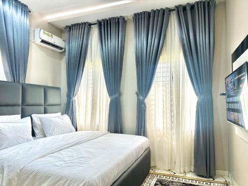 ein Schlafzimmer mit blauen Vorhängen und einem Bett vor einem Fenster in der Unterkunft Opic Shortlets in Agege