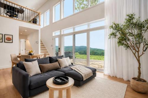 a living room with a black couch and a large window at Modern Comfort - Spa - Mountain - Chalet KNOX in Saint Come
