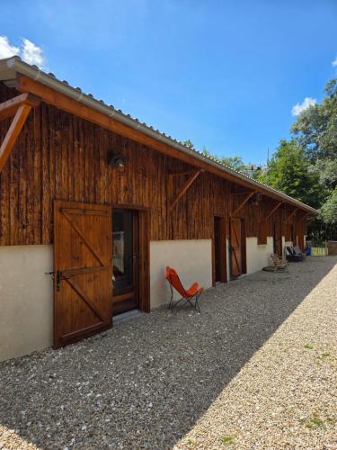 a red chair sits outside of a barn at Le ranch de Chant'alouette in Étauliers