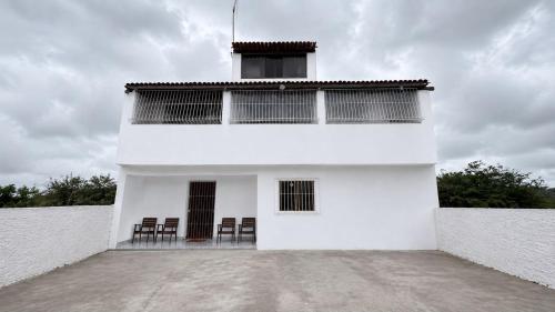 a white building with chairs in front of it at Casa de Temporada em Bezerros in Bezerros