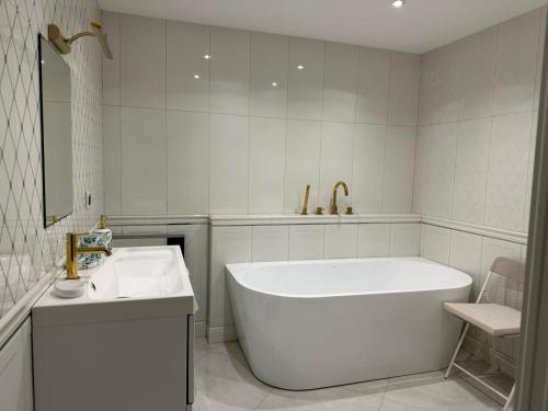 a white bathroom with a tub and a sink at Kościelnik Park Apartament in Lubań