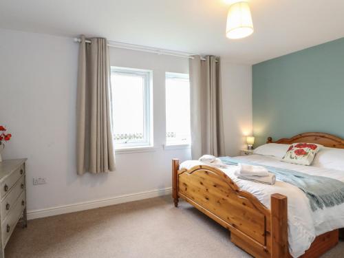 a bedroom with a wooden bed and a window at Poppies Cottage in Craignure