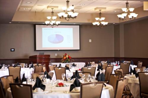 une salle de conférence avec des tables, des chaises et un écran dans l'établissement Cherokee Casino West Siloam Springs Resort, à West Siloam Springs