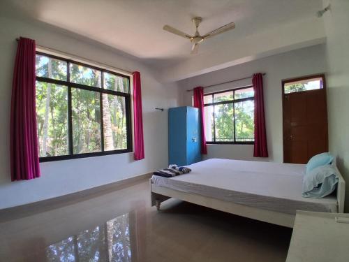 a bedroom with a bed and two windows at Rooms In Canacona in Canacona