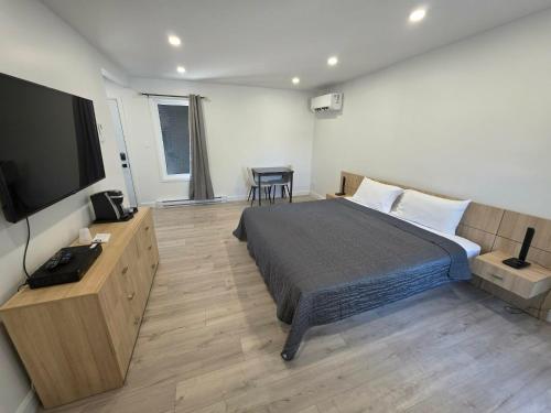 a bedroom with a bed and a flat screen tv at Le 2020 Charlevoix in La Malbaie
