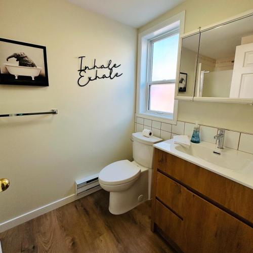 a bathroom with a toilet and a sink and a mirror at The Wineries are Calling! in Penticton