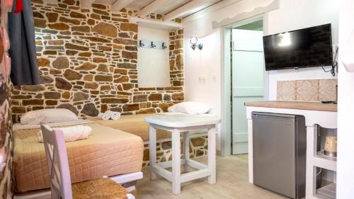 a living room with a table and a stone wall at Rodakas Rooms-Glikeria in LivadhokhÃ³rion