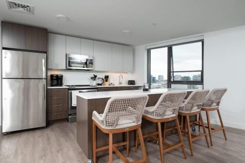 a kitchen with a bar with chairs and a refrigerator at Central Upscale 2BR Condo wGym Office & Parking in Cambridge