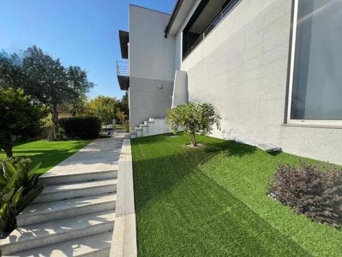 a house with a grass yard next to a building at Colina de Picoutos Moradia com piscina in Póvoa de Lanhoso