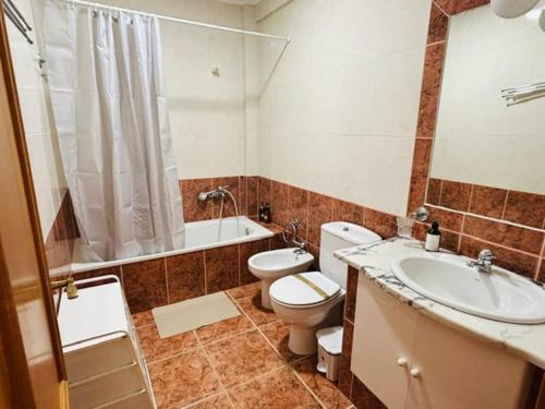 a bathroom with a toilet and a sink and a tub at SwordFish Beach Escape Apartment in Atouguia da Baleia