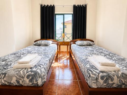 two beds sitting next to each other in a room at SwordFish Beach Escape Apartment in Atouguia da Baleia