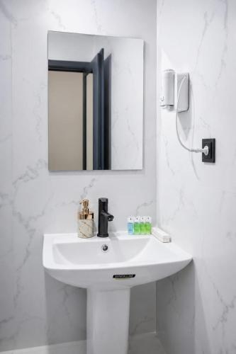 a white bathroom with a sink and a mirror at SkyGate Hotel in Pʼarakʼar