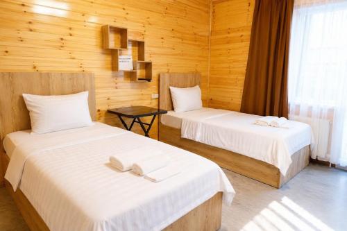 two beds in a room with wooden walls at SkyGate Hotel in Pʼarakʼar