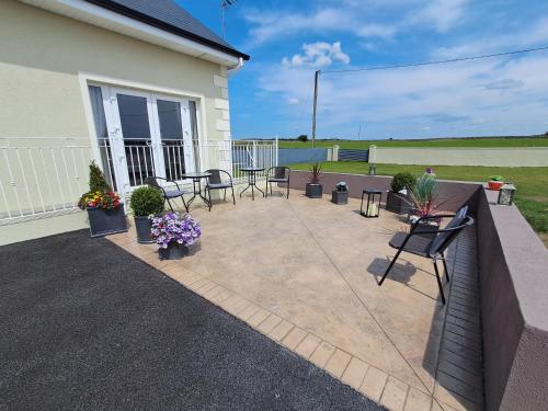 a patio with chairs and potted plants next to a house at Warm Spacious Three Bed Chalet in Galway