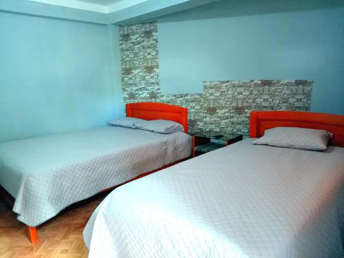 a bedroom with two beds and a stone wall at El REFUGIO DE MIS SUEÑOS in Yungay