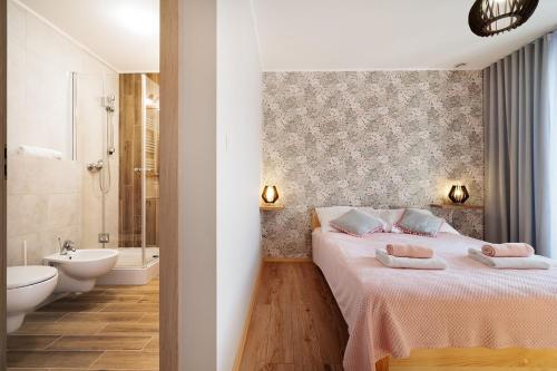 a bedroom with a bed and a bathroom with a sink at Bocian Apartamenty in Krynica Zdrój