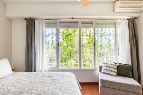 a bedroom with a bed and a window and a chair at Super duplex Martinez in Martínez