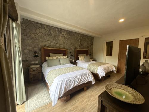 a bedroom with two beds and a stone wall at Anae en ValQuirico in Santeagueda