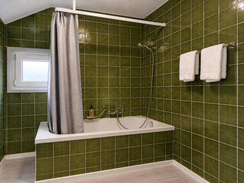 a green tiled bathroom with a tub and a shower at Rivalago - Lake front apartment on Lake Promenade in Brissago