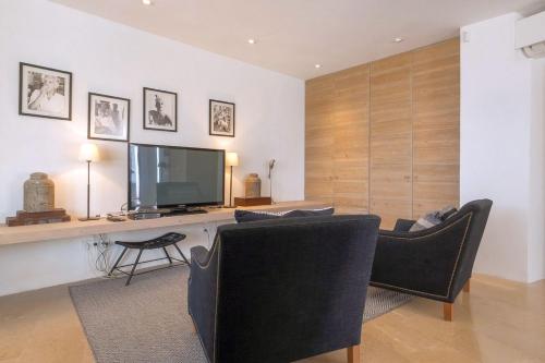 a living room with a television and a desk with chairs at Sunset Sea View Villa with Private Pool in Sant Josep de sa Talaia