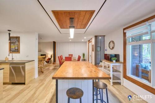 a kitchen and living room with a large wooden table at Le Rustique Moderne Detente - Lake Access in Pohénégamook