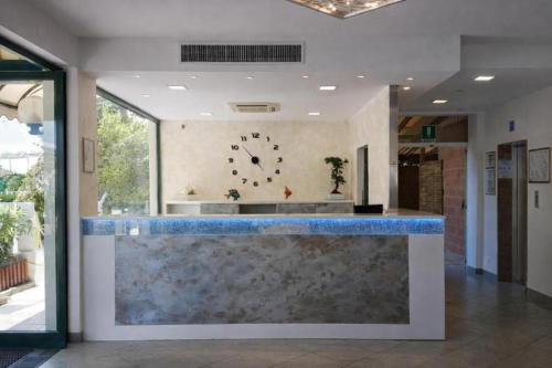 a lobby with a counter with a clock on the wall at Hotel Centrale FRONTE MARE in Milano Marittima