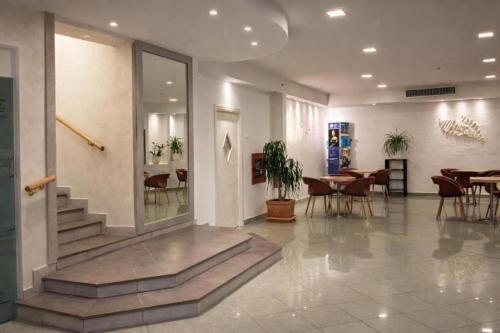a lobby with a staircase and tables and chairs at Hotel Centrale FRONTE MARE in Milano Marittima