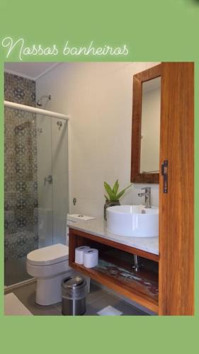a bathroom with a sink and a toilet and a mirror at Pousada e Restaurante Vila do Loro in Domingos Martins