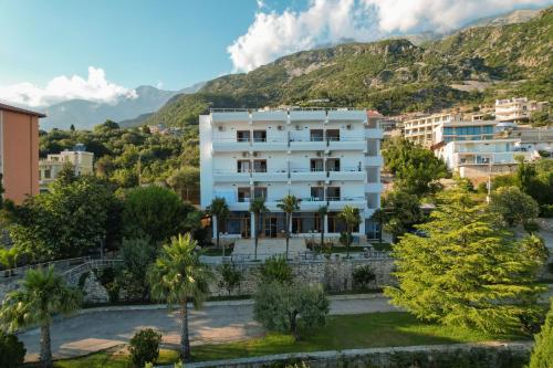 a white apartment building with mountains in the background at Hotel Palasa in Palasë