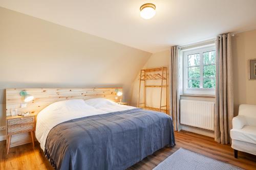 a bedroom with a bed and a chair and a window at Kreuzkate-Ostholstein in Manhagen