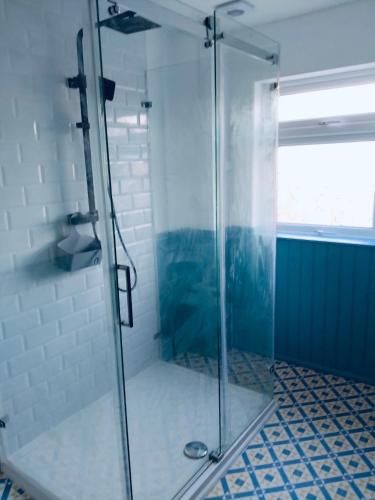 a shower with a glass door in a bathroom at Sandhurst guest house in Bedford