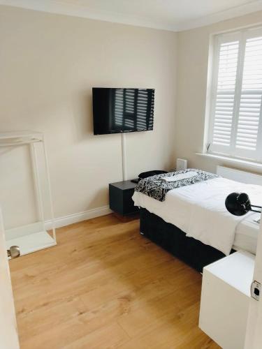 a bedroom with a bed and a flat screen tv at Sandhurst guest house in Bedford