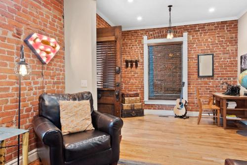 a living room with a leather chair and a brick wall at The Whittier Wonder in Denver