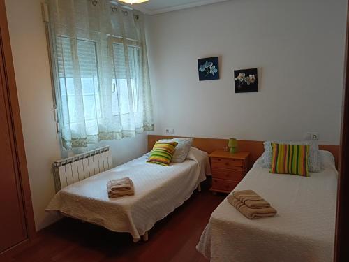 a bedroom with two beds and a dresser and a window at La Casa de Lines in Monforte de Lemos