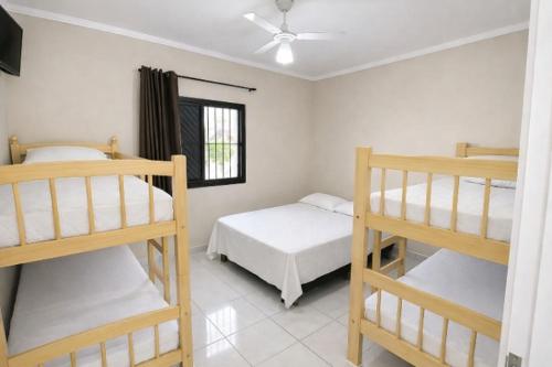 a bedroom with three bunk beds and a window at Apartamentos PraiaMar in Ilha Comprida