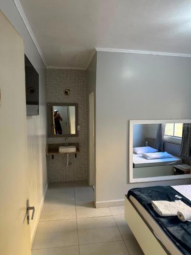 a bedroom with a bed and a mirror and a sink at Hotel Skala - Estacionamento Próprio no Local - 1 km Parque Antônio Pezzolo e 700 métros da Estação de Trem Prefeito Saladino in São Paulo