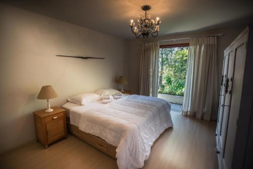 a bedroom with a bed with a chandelier and a window at Bosque Oriri in Rebouças
